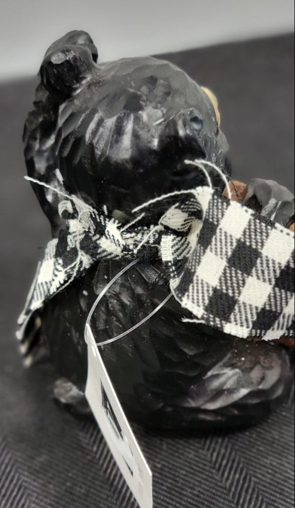 Small figurine Bear with a checkered scarf and sign on a textured surface