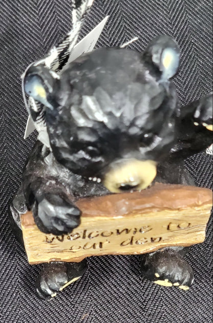 Decorative black bear figurine with a wooden plaque on a textured surface