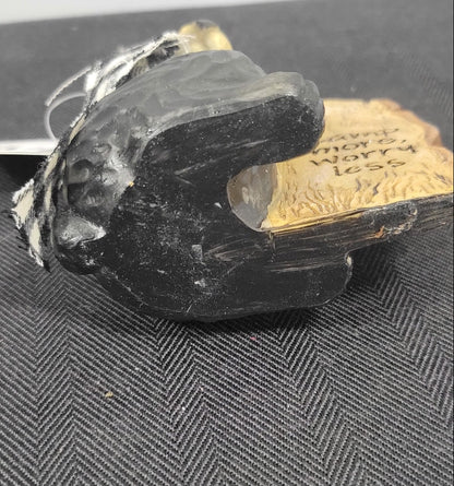 Black bear object on a textured black surface with text on a wooden block.