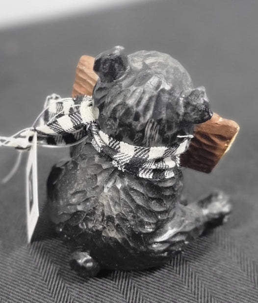Small bear figurine wearing a checkered scarf and sign.