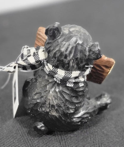 Small bear figurine wearing a checkered scarf and sign.