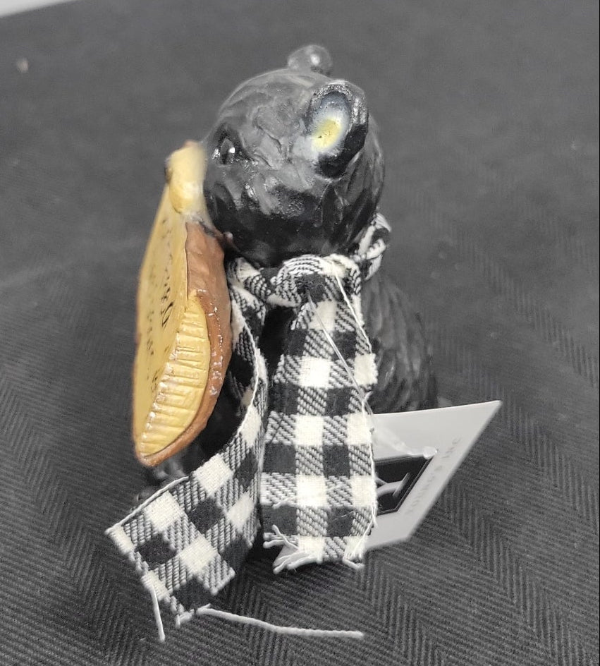 Small figurine of a baby black bear in a checkered scarf 